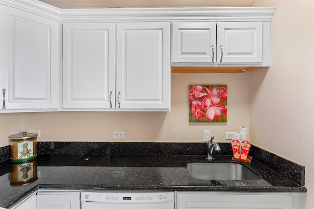 kitchen featuring dishwasher, sink, dark stone countertops, and white cabinets