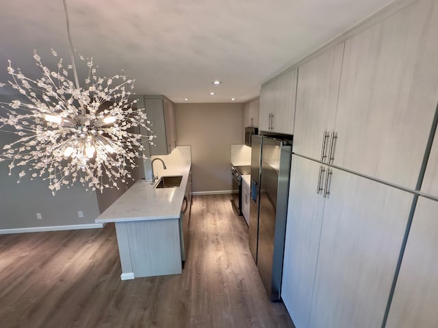 kitchen featuring dark hardwood / wood-style flooring, stainless steel appliances, light stone counters, and sink