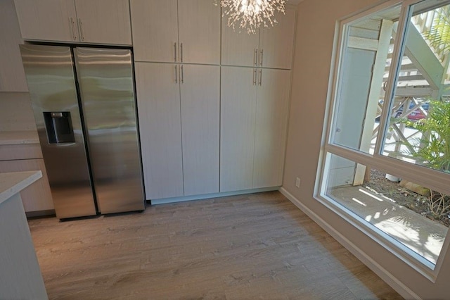 interior space with an inviting chandelier, a wealth of natural light, and light hardwood / wood-style flooring