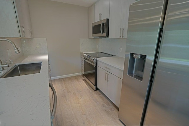 kitchen featuring white cabinets, sink, stainless steel appliances, and light hardwood / wood-style flooring