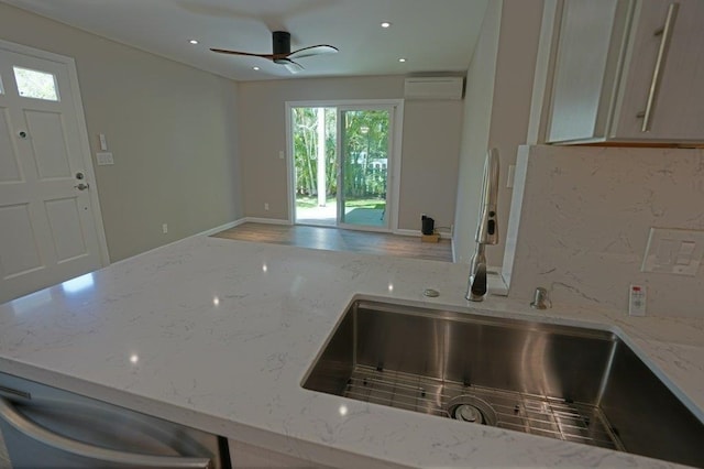 kitchen featuring light stone counters, sink, ceiling fan, and a wall mounted air conditioner