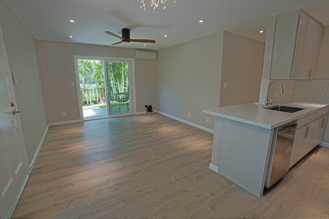 kitchen with light wood-type flooring, sink, an AC wall unit, dishwasher, and white cabinetry