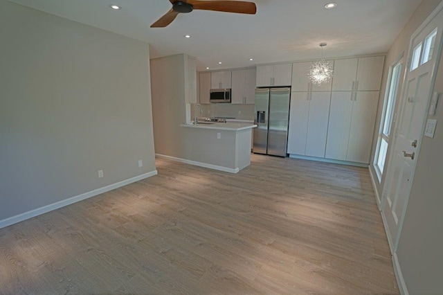 kitchen with decorative light fixtures, light wood-type flooring, and stainless steel appliances