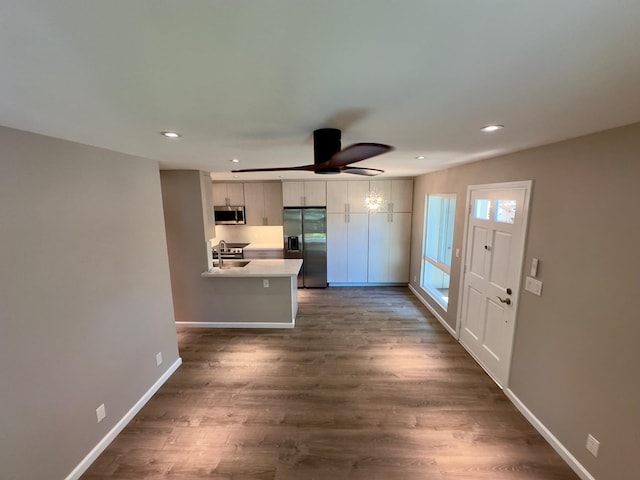 kitchen with white cabinets, dark hardwood / wood-style flooring, kitchen peninsula, and stainless steel appliances