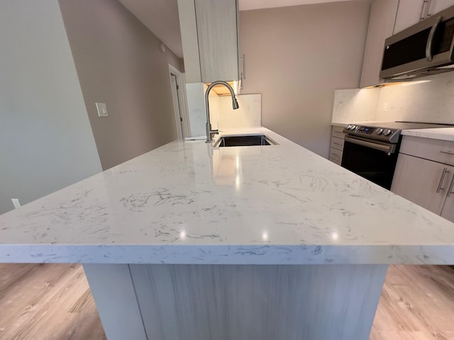 kitchen featuring light stone counters, light hardwood / wood-style floors, sink, and stainless steel appliances