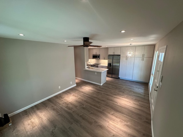 kitchen featuring sink, dark hardwood / wood-style floors, ceiling fan, appliances with stainless steel finishes, and kitchen peninsula