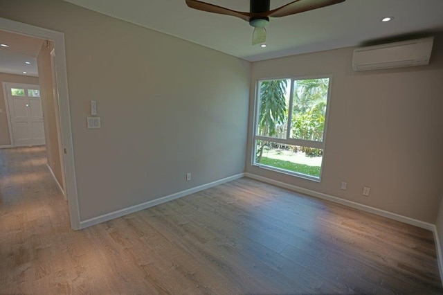 empty room featuring an AC wall unit, ceiling fan, and light hardwood / wood-style flooring