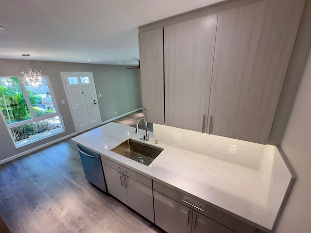 kitchen featuring dishwasher, light stone countertops, wood-type flooring, and sink