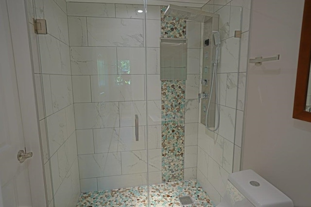 bathroom with a shower with shower door and toilet