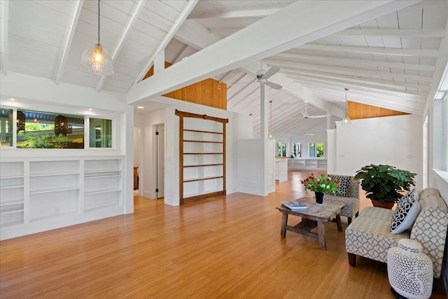 sitting room featuring light wood-type flooring, beamed ceiling, ceiling fan, and wooden ceiling