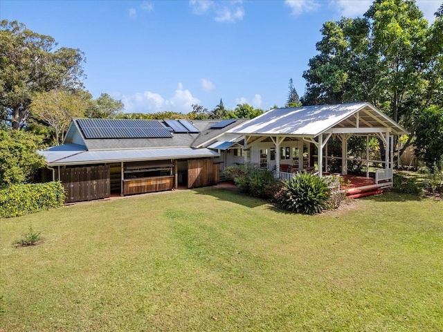 rear view of property featuring solar panels and a lawn