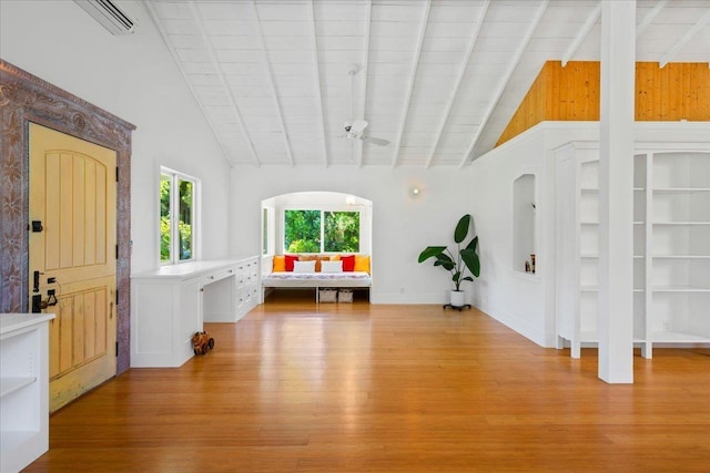 interior space featuring beamed ceiling, light wood-type flooring, and high vaulted ceiling