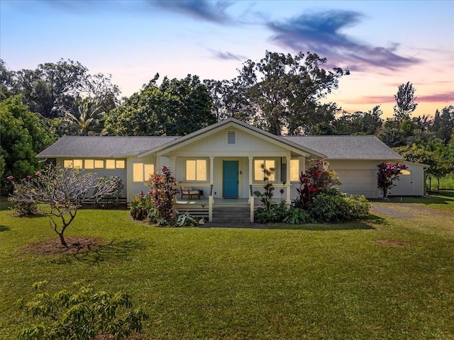 view of front of property featuring a garage, a front lawn, covered porch, and driveway