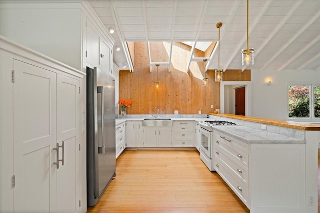 kitchen with wooden walls, white range with gas cooktop, a peninsula, high end fridge, and a sink