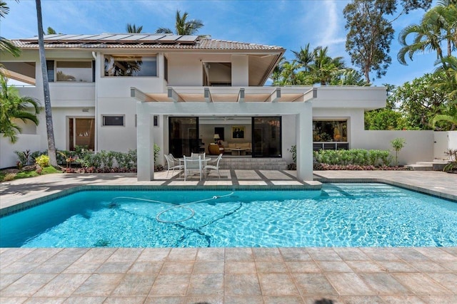 back of house featuring solar panels, a patio, and a fenced in pool