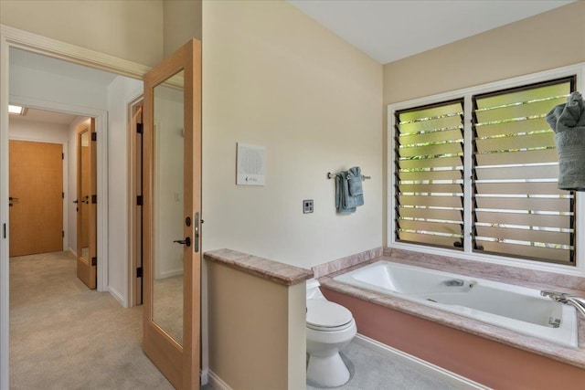 bathroom with a tub to relax in and toilet