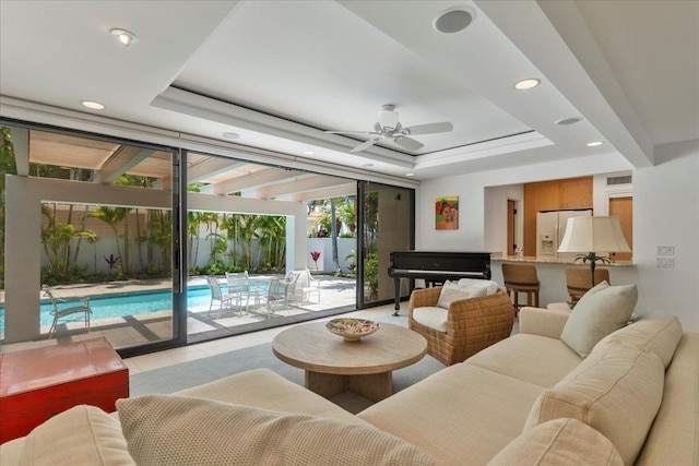 tiled living room with a tray ceiling and ceiling fan