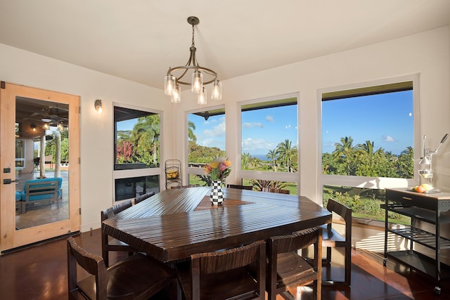 dining area with plenty of natural light, dark wood finished floors, and an inviting chandelier