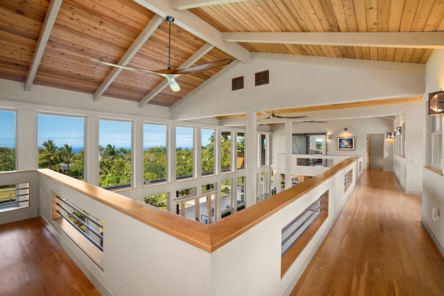 hallway with hardwood / wood-style floors, beamed ceiling, wooden ceiling, and a healthy amount of sunlight