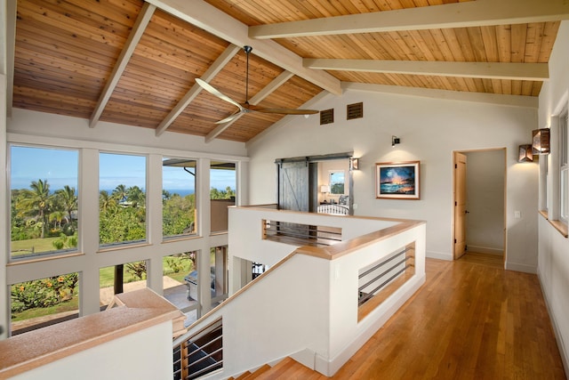 interior space with light wood-type flooring, a barn door, wood ceiling, and beam ceiling