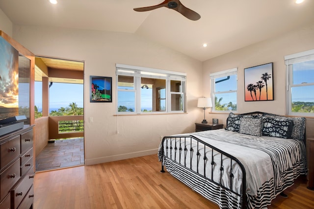 bedroom with vaulted ceiling, access to outside, multiple windows, and wood finished floors