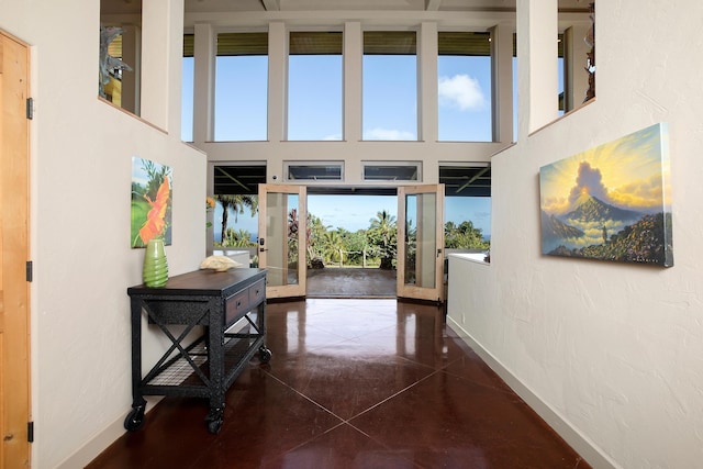 entryway with tile patterned flooring, a high ceiling, and baseboards