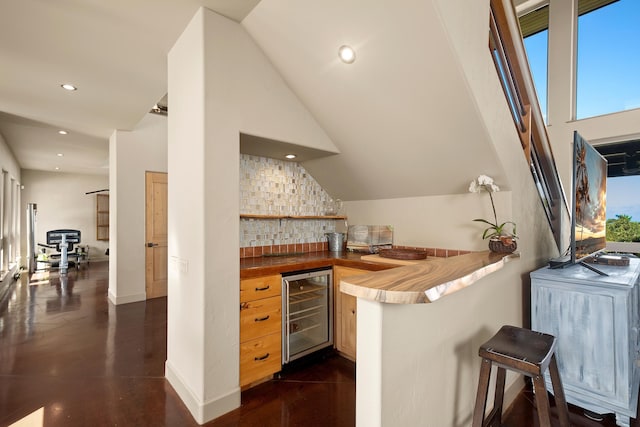 bar with lofted ceiling, wine cooler, indoor wet bar, backsplash, and recessed lighting