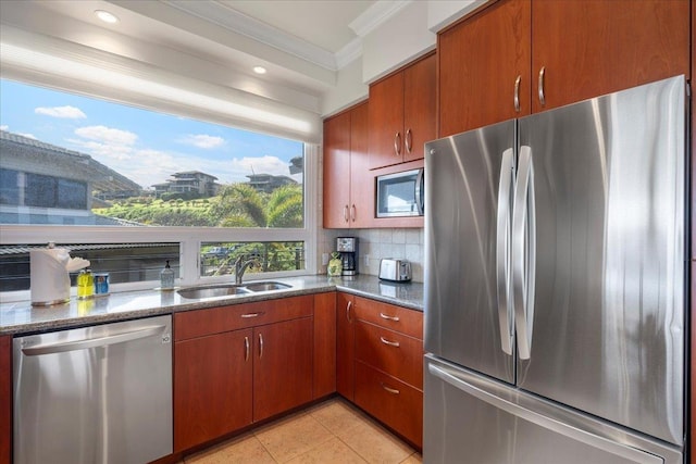 kitchen featuring a sink, dark stone counters, appliances with stainless steel finishes, crown molding, and decorative backsplash