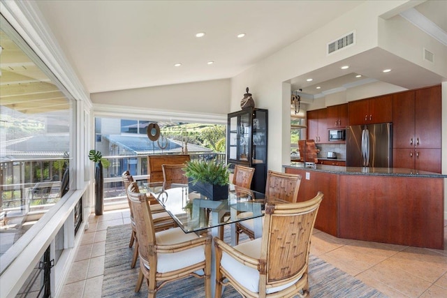 dining room featuring light tile patterned floors, visible vents, and vaulted ceiling