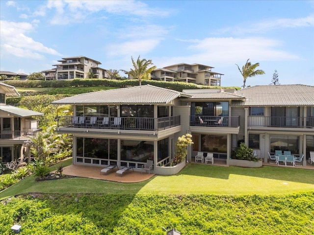 rear view of house featuring a yard, a patio area, and a balcony