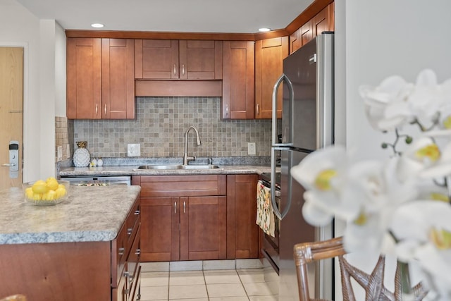 kitchen with light tile patterned floors, a sink, stainless steel appliances, light countertops, and backsplash