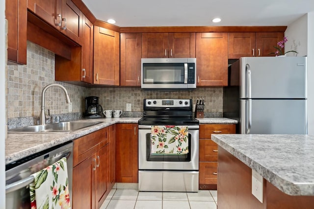 kitchen featuring light tile patterned floors, tasteful backsplash, light countertops, appliances with stainless steel finishes, and a sink