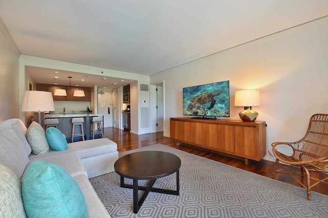 living room with dark hardwood / wood-style floors, crown molding, and sink