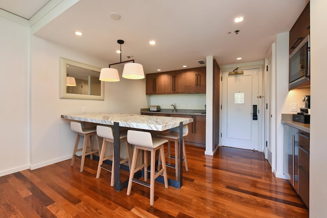 kitchen featuring a breakfast bar, dark hardwood / wood-style flooring, kitchen peninsula, and black microwave