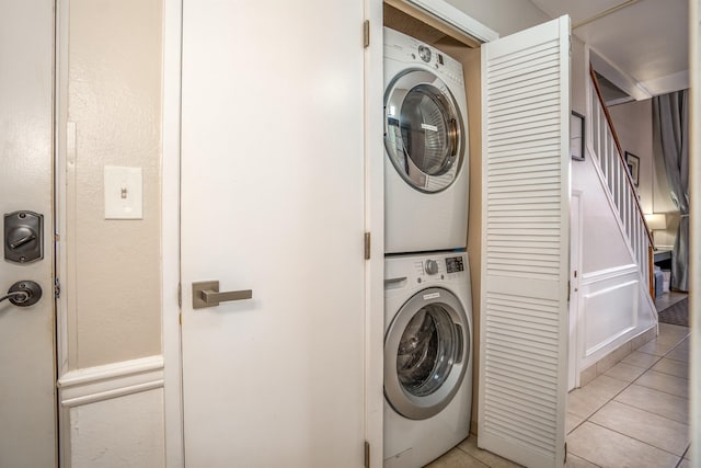 clothes washing area featuring stacked washer and clothes dryer and light tile flooring