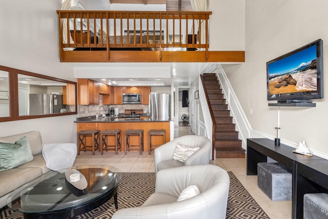 living room with a towering ceiling, sink, and light tile floors