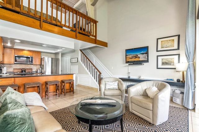 living room featuring a high ceiling, sink, and light tile floors