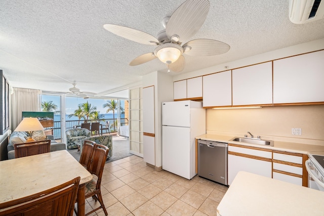 kitchen with stainless steel dishwasher, expansive windows, sink, white cabinets, and white fridge