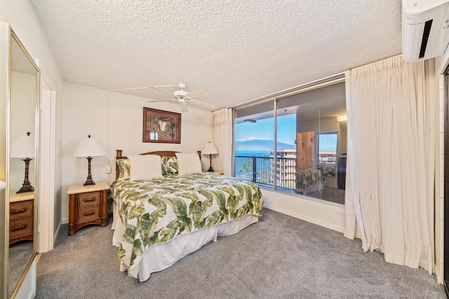 carpeted bedroom with a wall mounted AC, a textured ceiling, access to outside, and ceiling fan