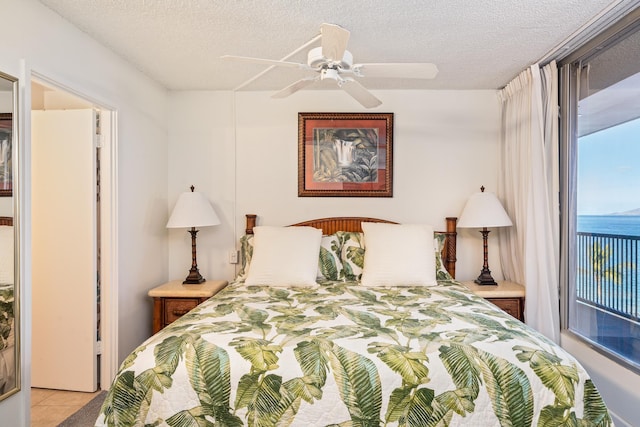 tiled bedroom featuring a textured ceiling, a water view, and ceiling fan