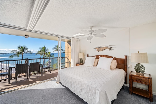 carpeted bedroom with access to exterior, a textured ceiling, a water view, and ceiling fan