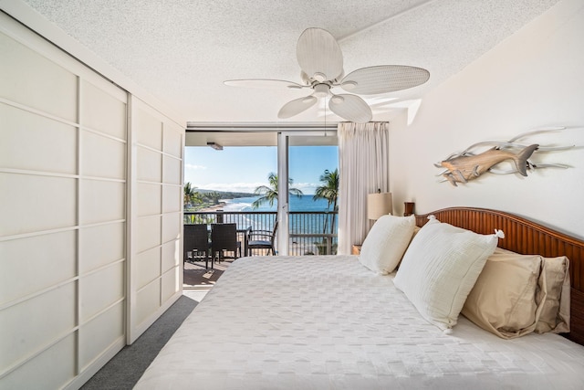 carpeted bedroom featuring access to exterior, a textured ceiling, and ceiling fan