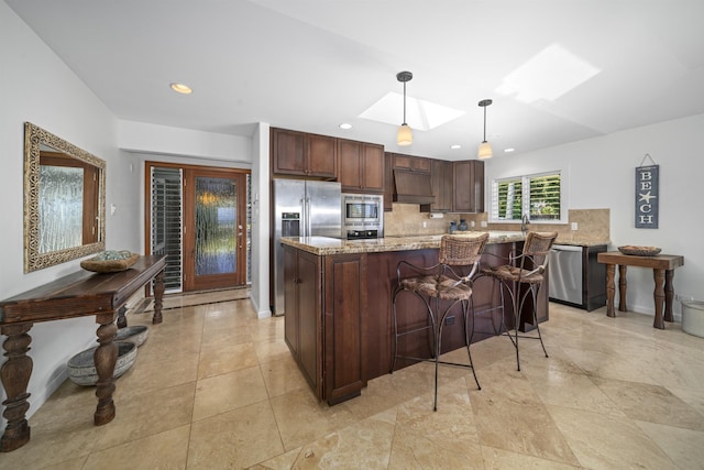 20 Hui Rd I 41, Lahaina, HI 96761 - kitchen featuring appliances with stainless steel finishes, a skylight, tasteful backsplash, premium range hood, and hanging light fixtures