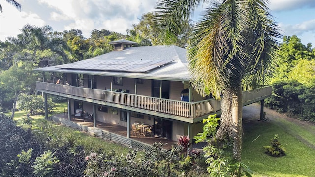 back of house featuring a balcony and a lawn