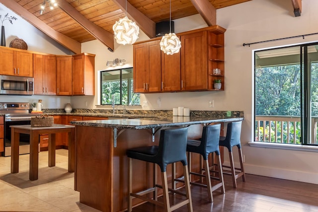 kitchen with pendant lighting, appliances with stainless steel finishes, wooden ceiling, and vaulted ceiling with beams