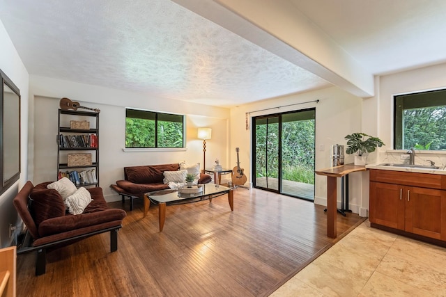 living room featuring a textured ceiling, sink, and light tile floors