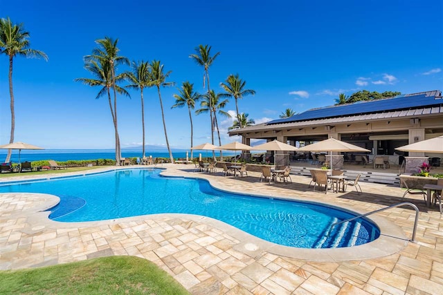 view of swimming pool with a patio area and a water view