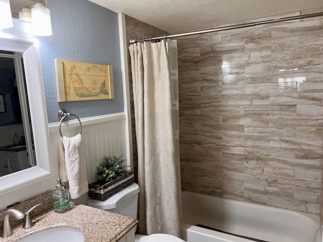 full bath featuring a textured ceiling, a textured wall, toilet, wainscoting, and shower / bathtub combination with curtain