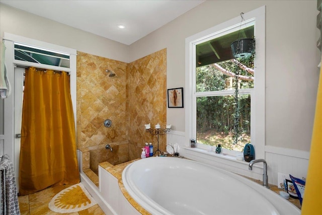 full bathroom with tile patterned floors, a bath, tiled shower, and a wainscoted wall