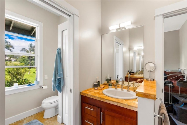 bathroom featuring toilet, baseboards, vanity, and tile patterned flooring